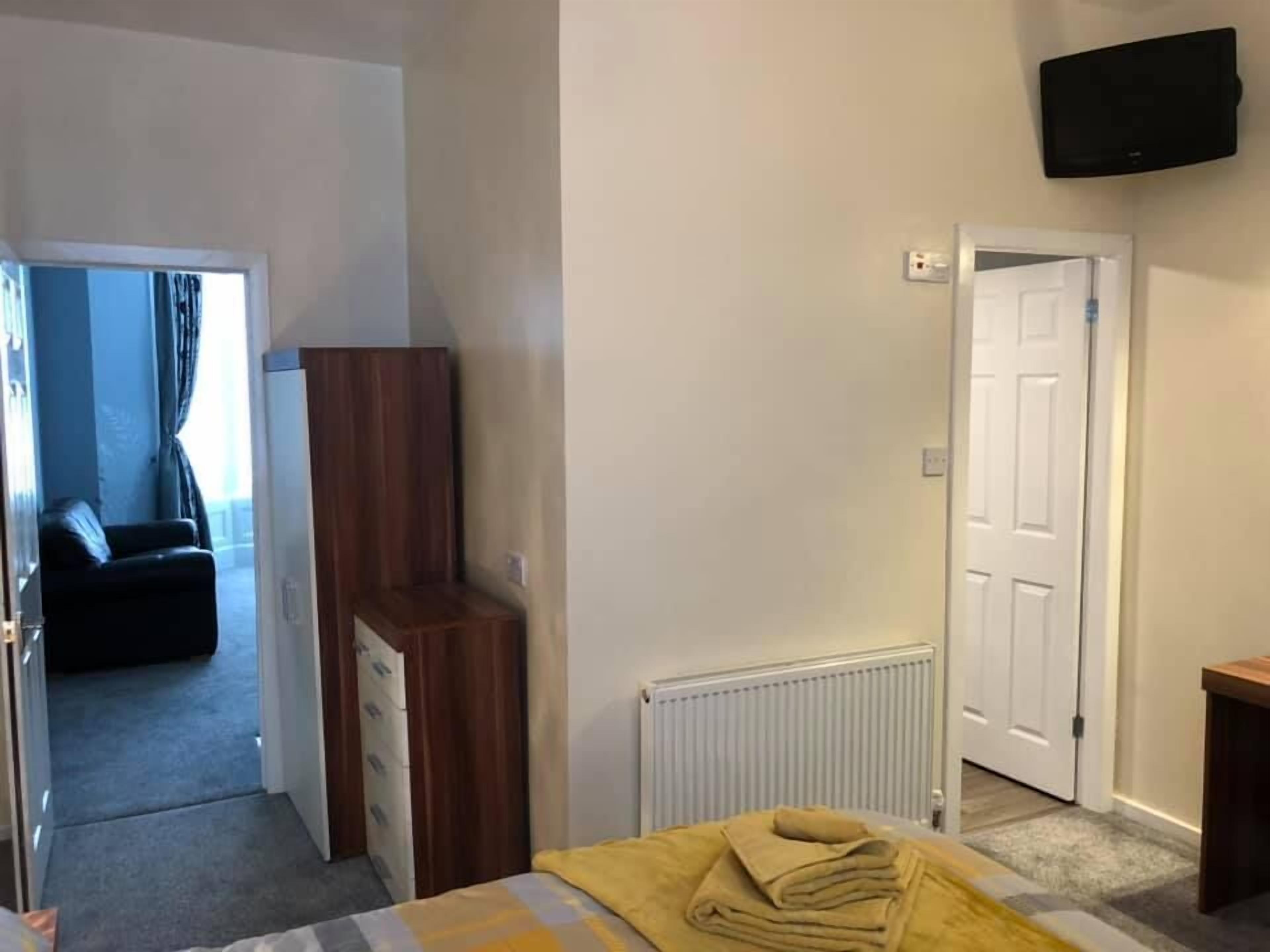 Un dormitorio con cama, cómoda de madera, radiador y televisor montado en la pared.