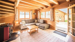 A wooden cabin interior with a sofa, a table, and a fireplace. - Chalets Trafögl (Val Muestair)