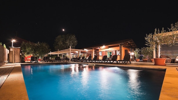 A swimming pool with lounge chairs and a covered seating area at night. - Country Resort Le Due Ruote (Grosseto)