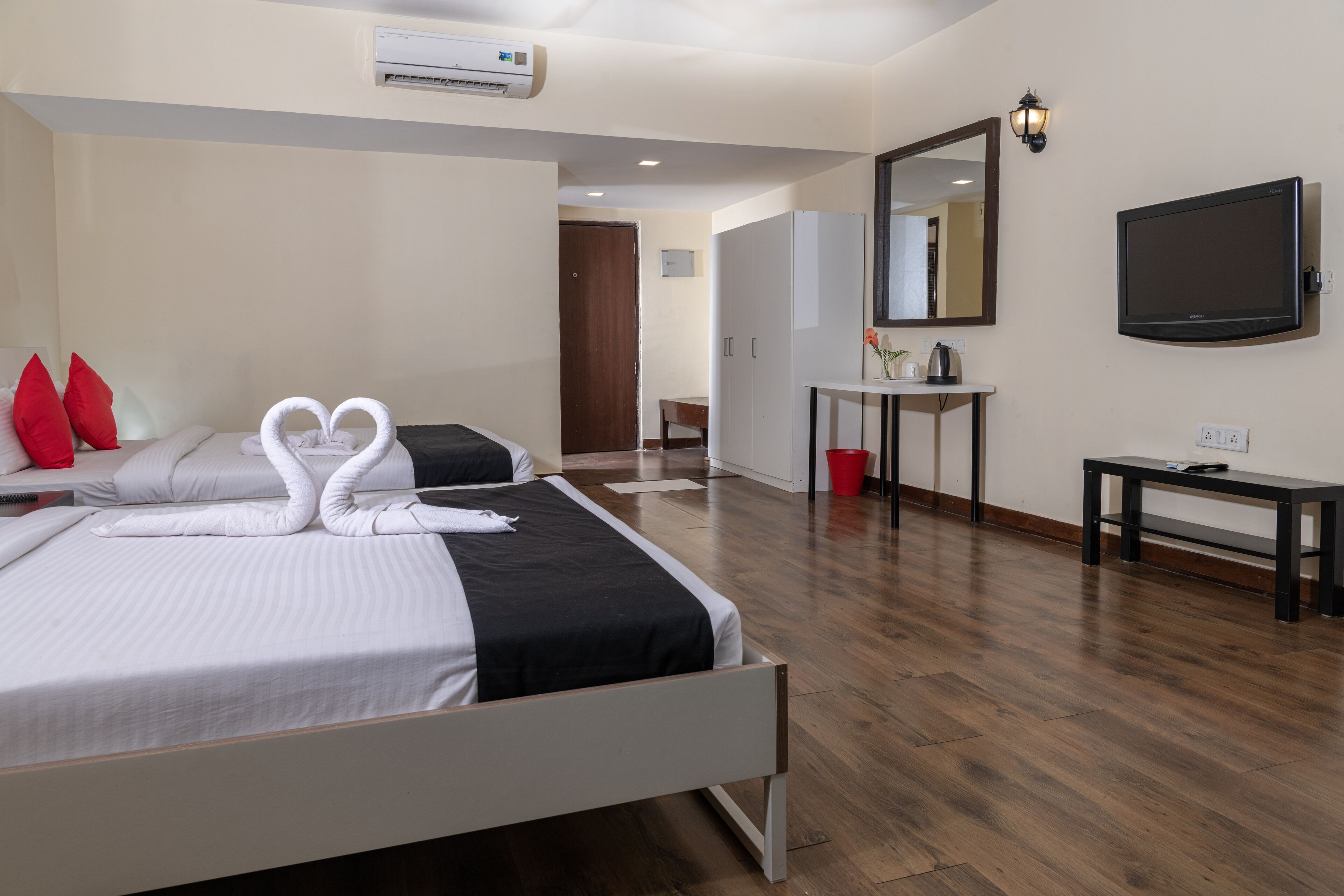 A hotel room with two beds, a TV, a desk, and a mirror.