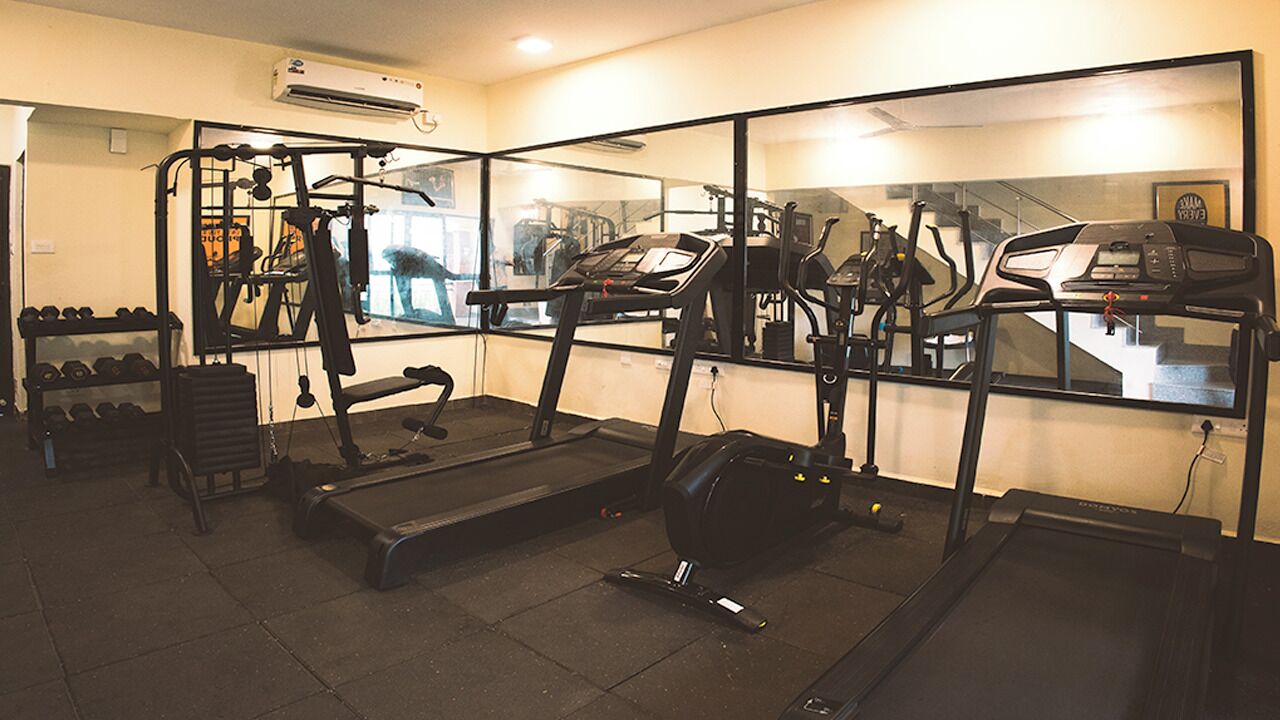 Un gimnasio con cintas de correr, elípticas y pesas libres.