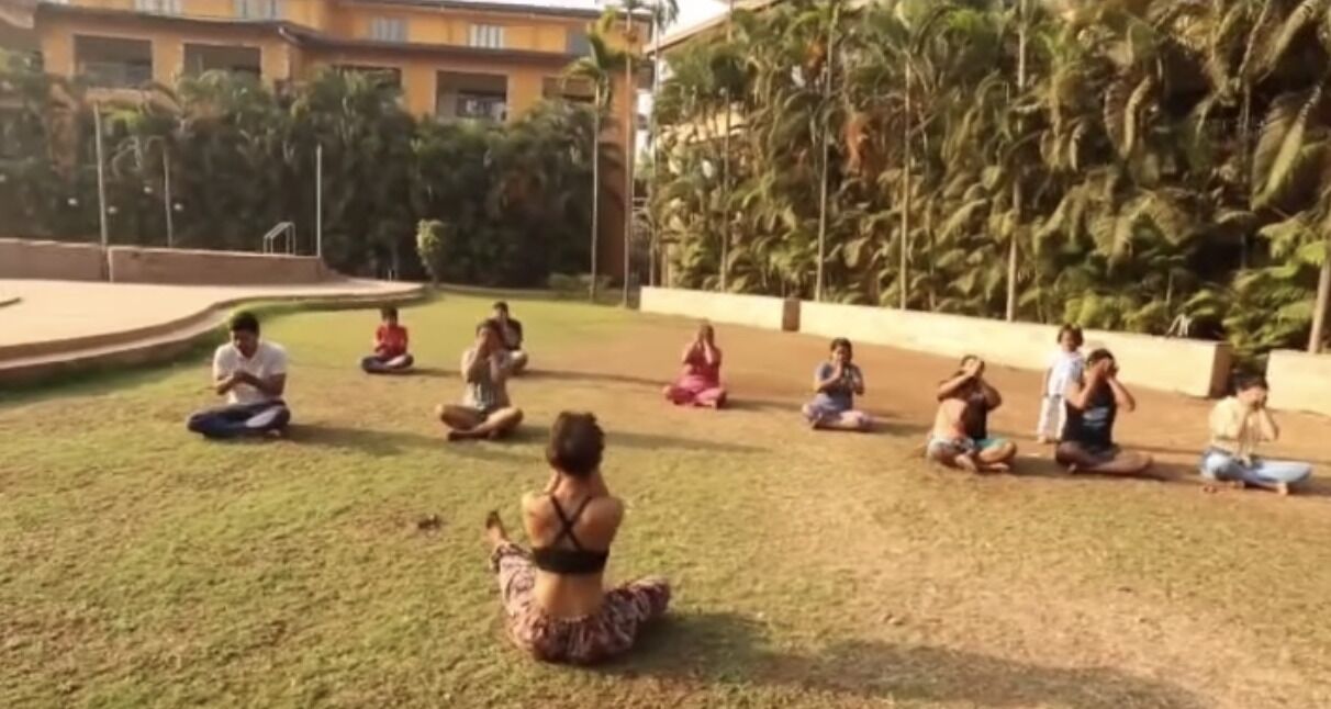 A group of people sitting in a circle on grass outdoors.