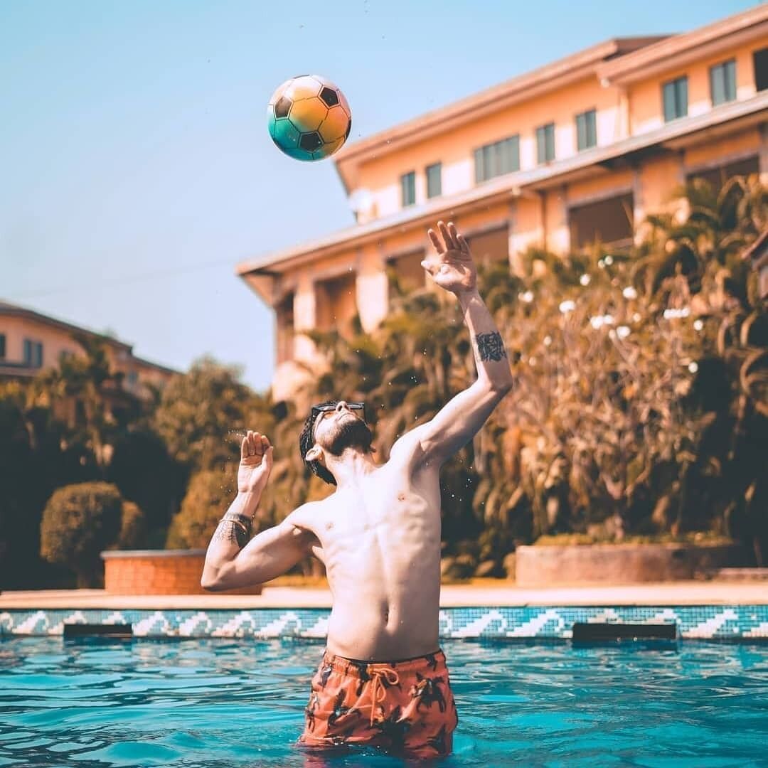 A person playing with a soccer ball in a swimming pool.