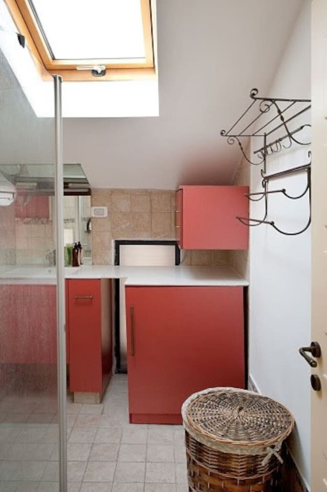 A compact kitchen with a skylight, a red refrigerator, and a wicker basket.