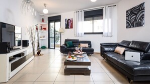 A modern living room with a black leather sofa, a white entertainment unit, and a coffee table with decorative items.