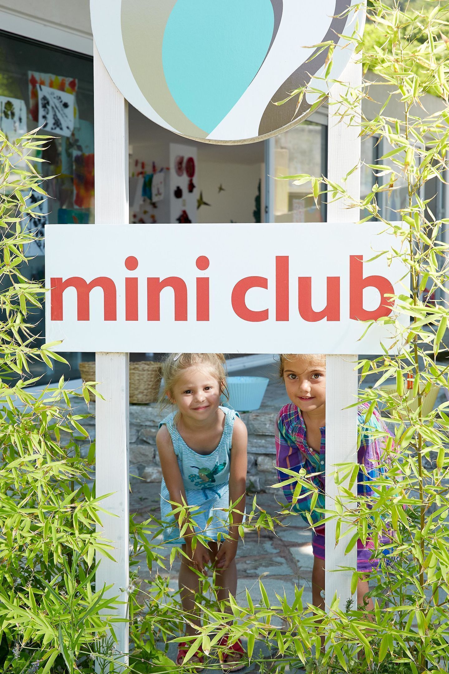 A sign for "mini club" with a child in a blue dress standing in front.