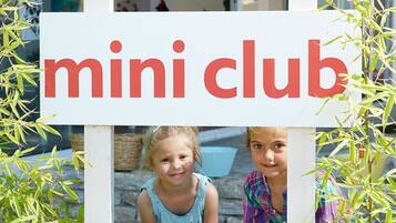 A sign for "mini club" with a child in a blue dress standing in front.