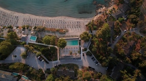 Ett flygbildsbild av en badort vid kusten med en strand, flera pooler och en parkeringsplats.