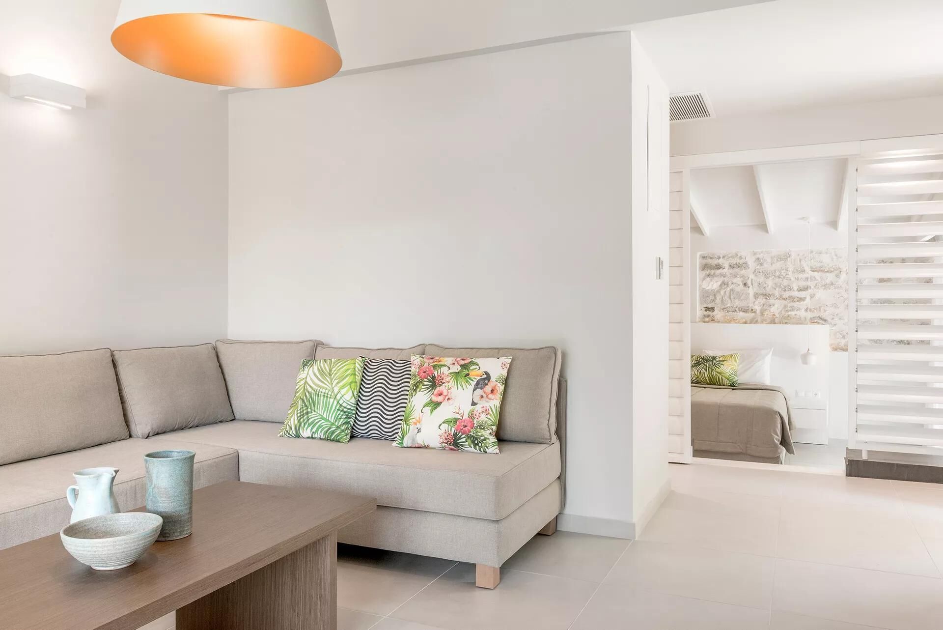 Un salon moderne avec un canapé beige, une table basse en bois et une lampe suspendue.