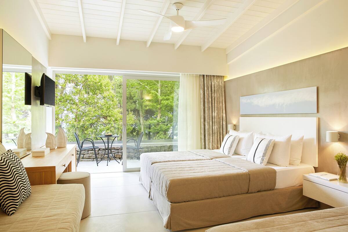 A modern bedroom with a large bed, a desk, and a TV.