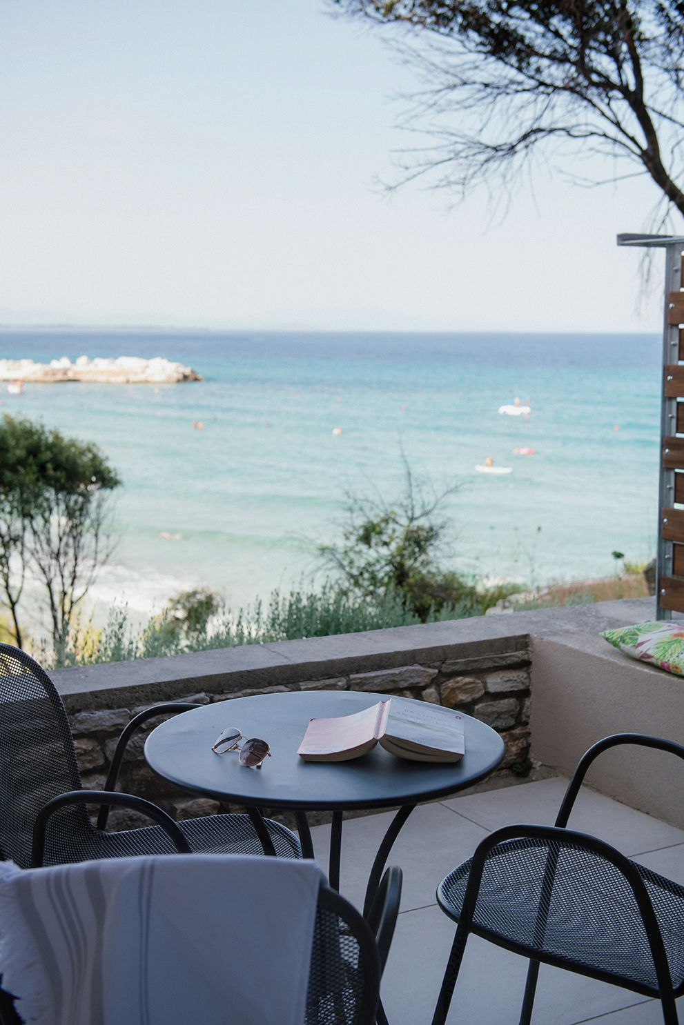 A patio with a round table, chairs, and a view of the sea.
