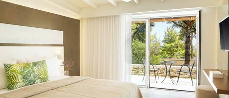 A bedroom with a large bed, a desk, and a view of the outdoors.
