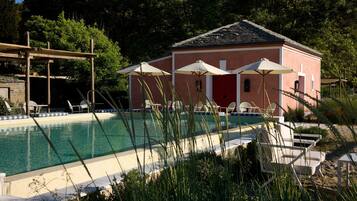 Ein Poolbereich mit Gebäude, Sitzgelegenheiten im Freien und einer Pergola.