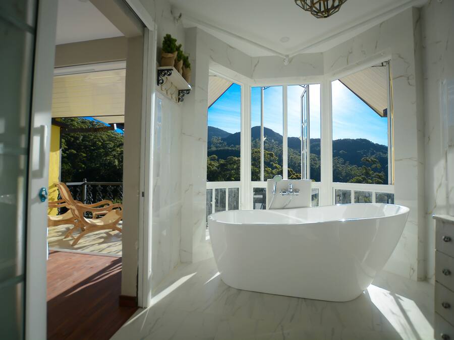A modern bathroom with a freestanding bathtub, large windows, and a view of mountains.