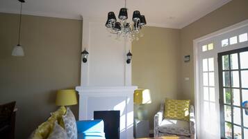 A living room with a fireplace, a chandelier, and a view through a large window.