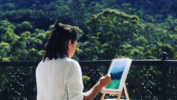 A person painting a landscape on an easel with a mountain in the background.