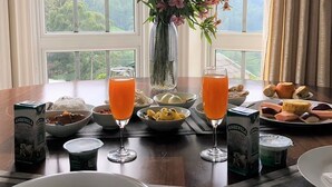 A table set with breakfast items, including bowls of fruit, cheese, and bread, and two glasses of orange juice. - Luxe Wilderness (Nuwara Eliya)