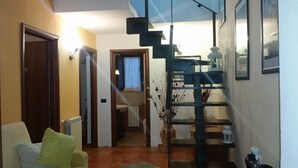 A hallway with a staircase, a chair with a green cushion, and a vase with dried plants. - B&B Mannala' (Agrigento)