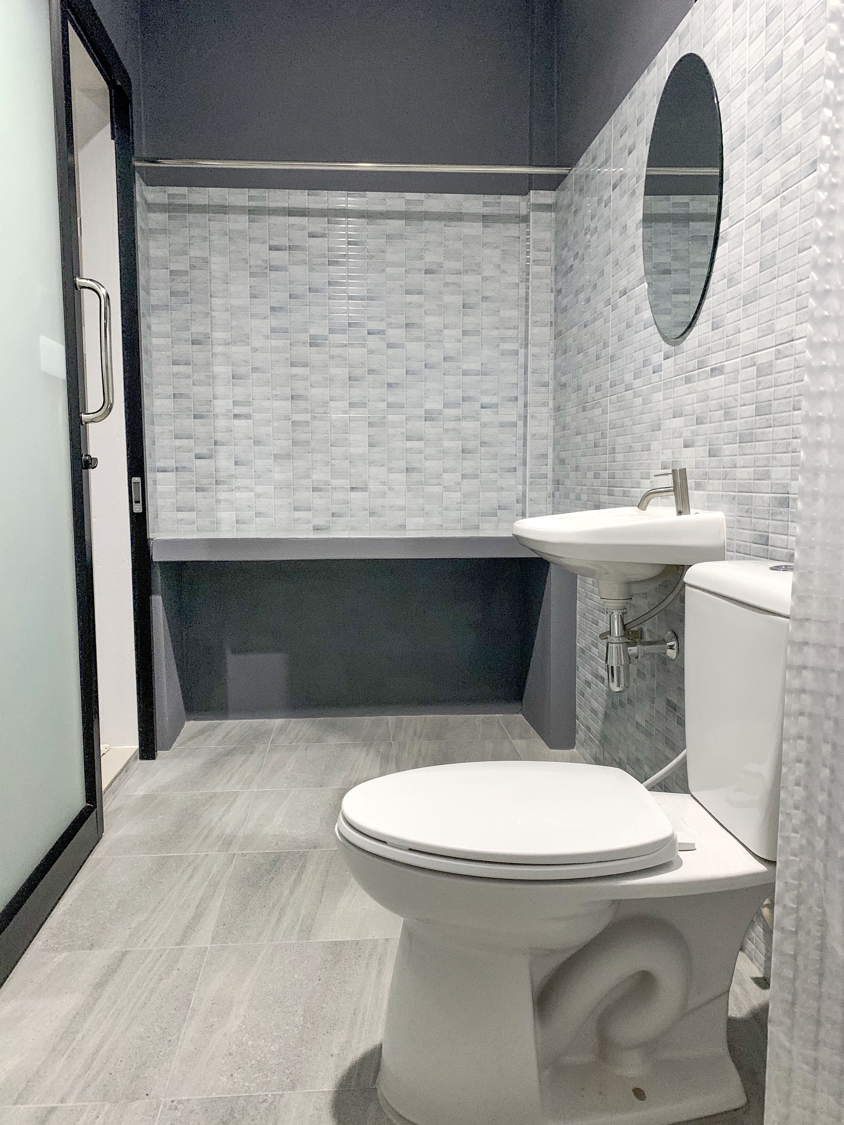 A modern bathroom with a white toilet, a sink, and a shower area.