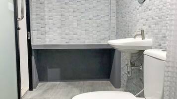A modern bathroom with a white toilet, a sink, and a shower area.