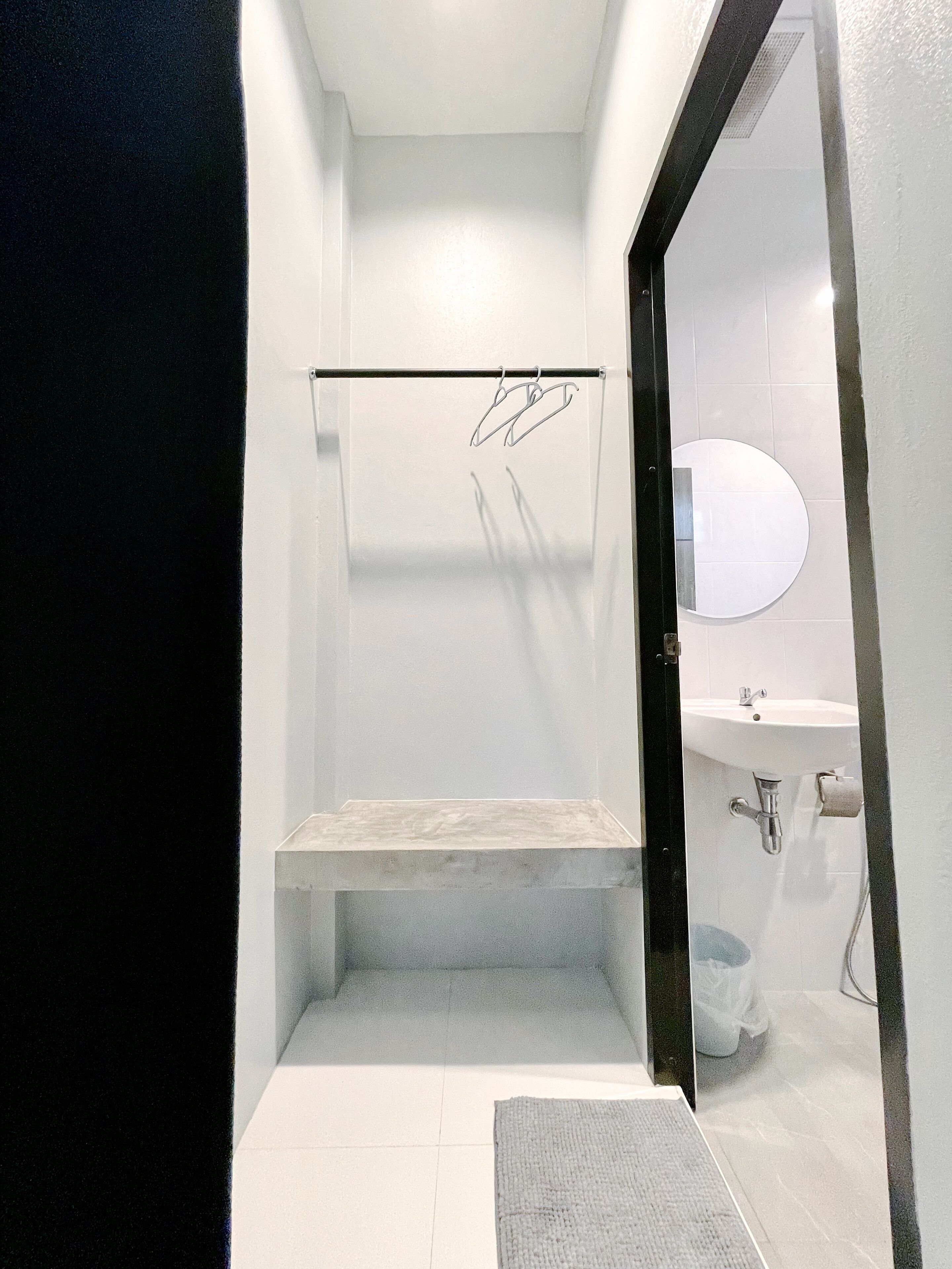 A small, modern bathroom with a white sink, mirror, and shower area.