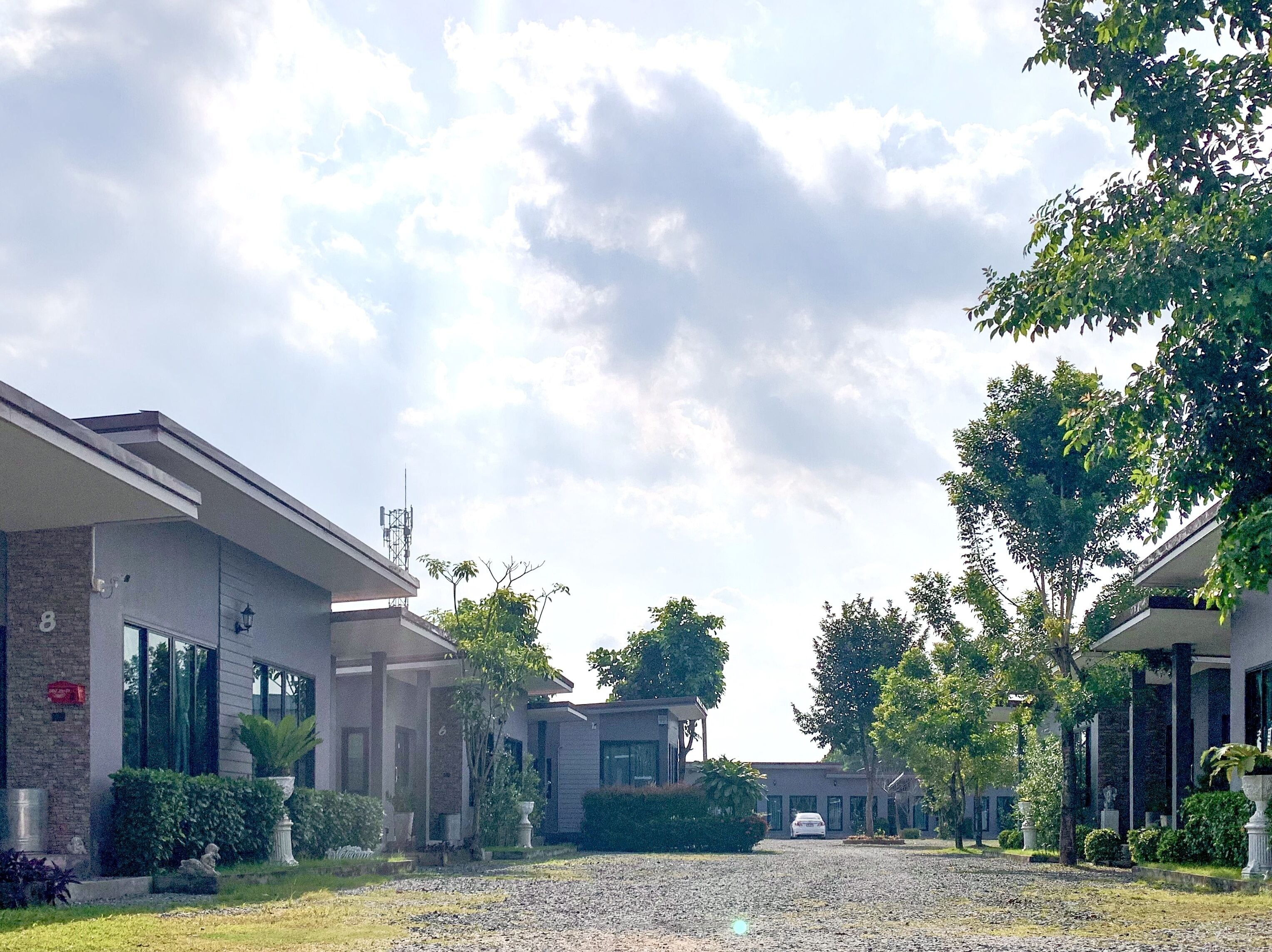 A modern building with a gravel driveway, surrounded by well-maintained greenery and trees.