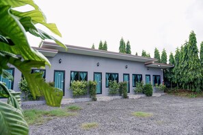 A modern building with a grey facade, multiple windows with teal curtains, and a gravel driveway. - Lamer Ville Resort (Chanthaburi)