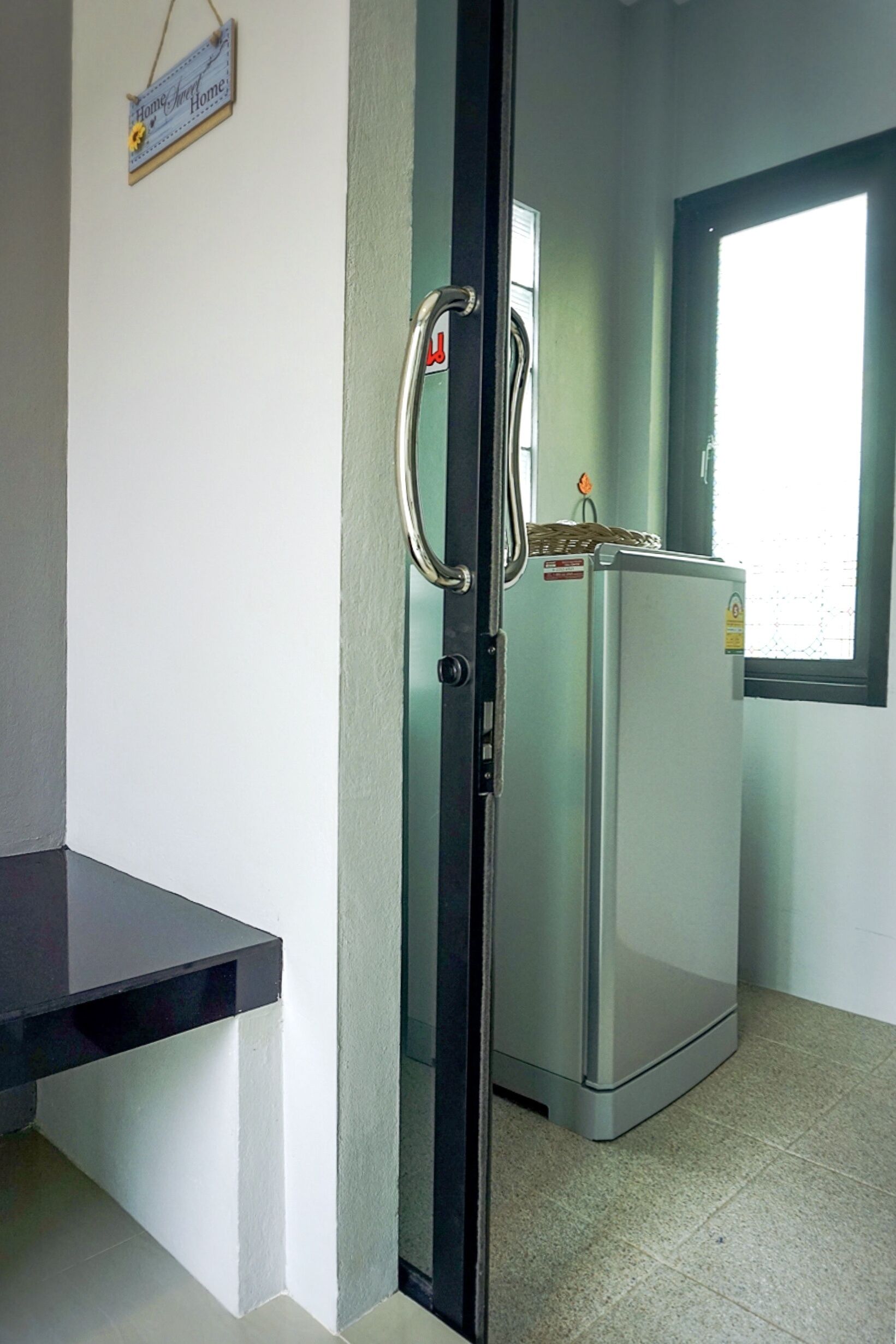 A kitchen with a refrigerator, a window, and a door with a handle.