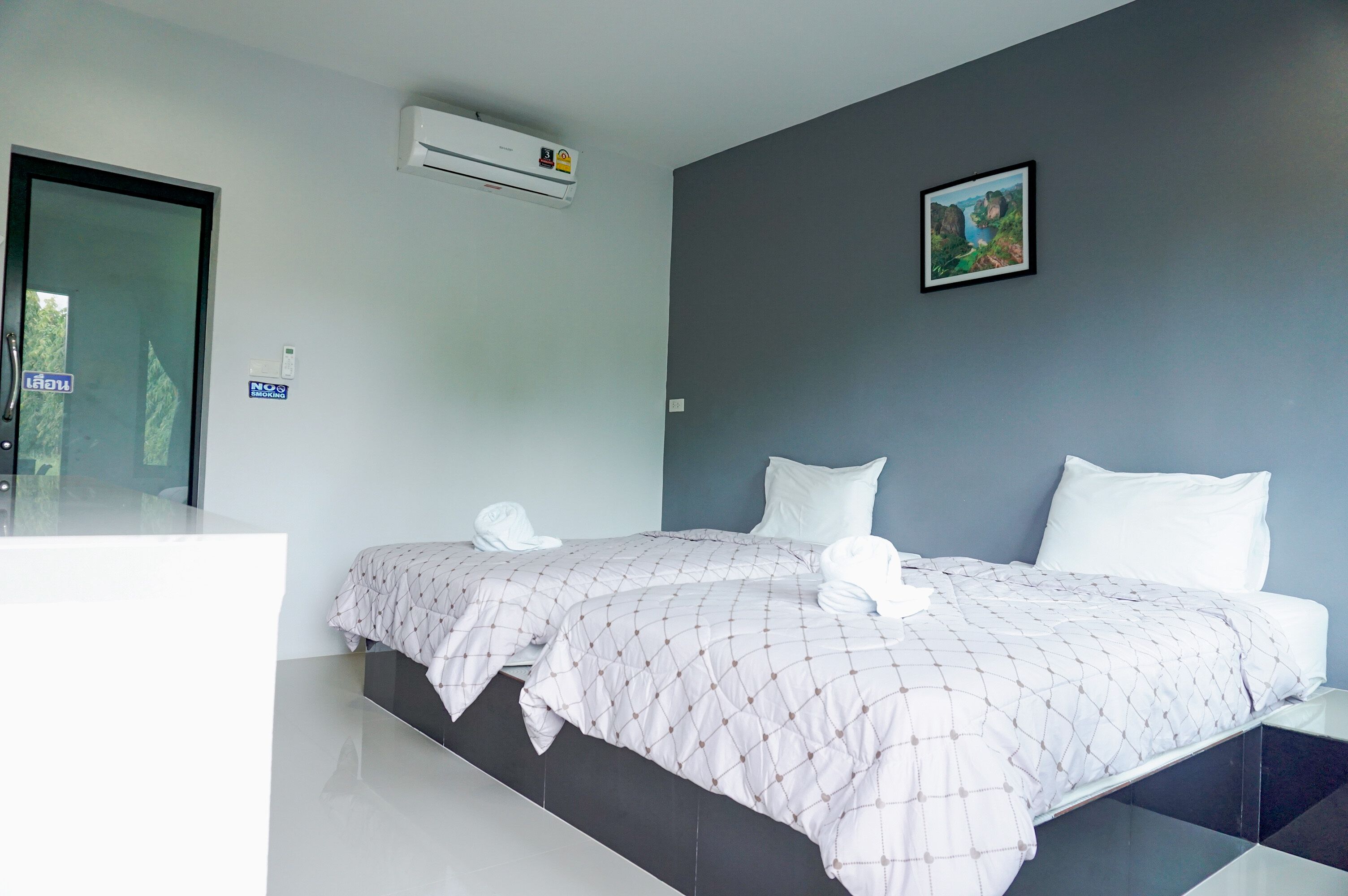 A hotel room with two beds, a large window, and an air conditioning unit.