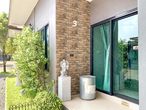 A building with a stone facade, a number '3' sign, a statue, and a metal barrel. - Lamer Ville Resort (Chanthaburi)