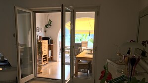 An open door leading to a dining area with a table and chairs, a hanging plant, and a view of the outdoors. - Villa Kaissini (Orselina)