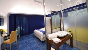 A hotel room with a bed, a desk with a chair, a bathroom with a sink and mirror, and a shower area. - Aquae Romanae Bed and Breakfast Sorrento (Sorrento)