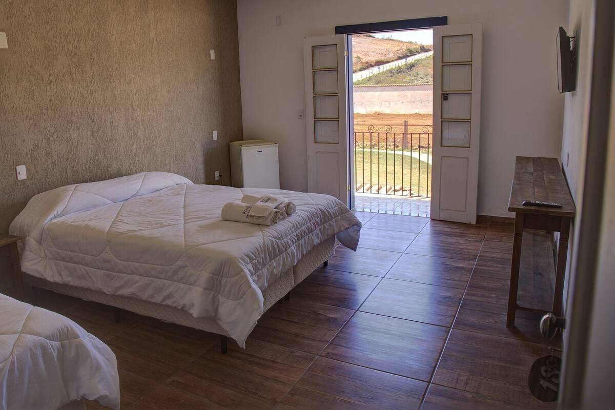 Un dormitorio con cama, una mesita, un radiador y una puerta que da a un balcón.