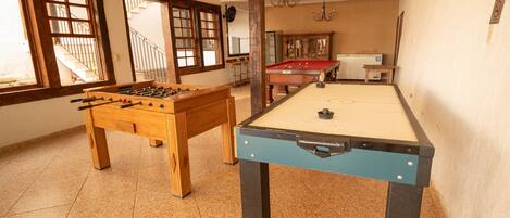 Una habitación con mesa de fútbol, mesa de billar y mesa de aficiones.