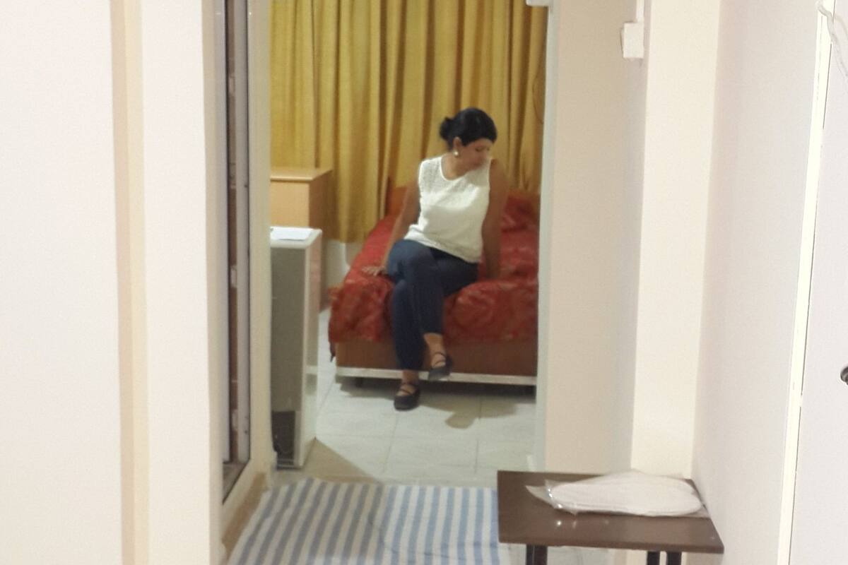 A hotel room with a bed, a small table, and a mirror.