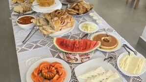 A buffet table with various food items including bread, pastries, fruits, and desserts. - Pousada Tiradentes (Tiradentes)