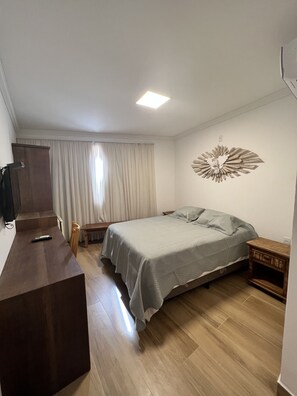 Un dormitorio con cama, mesitas de noche, un escritorio de madera y un amplio elemento decorativo en la pared.