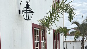 A white building with red window frames and a black lion statue in the yard. - Pousada Tiradentes (Tiradentes)