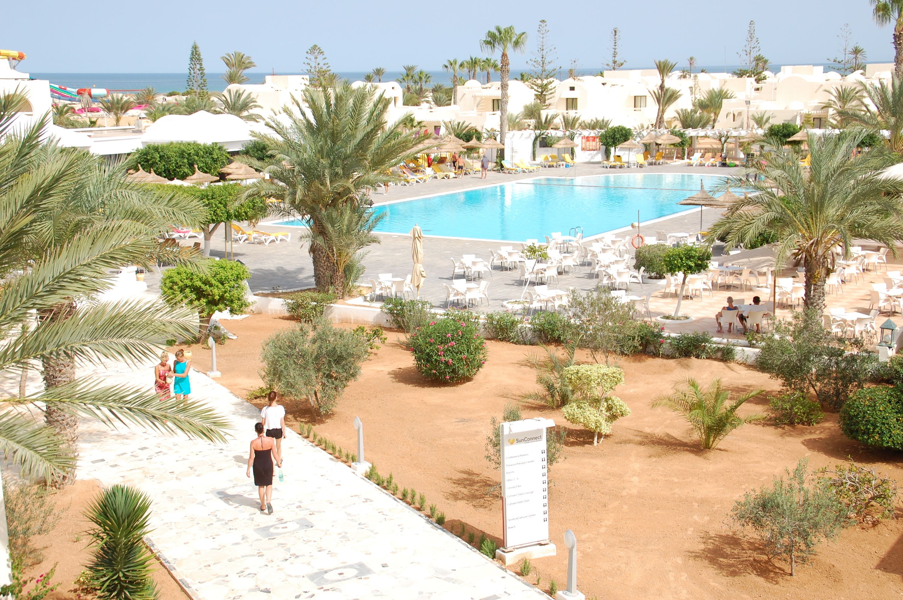 A resort with a swimming pool, palm trees, and lounge chairs.