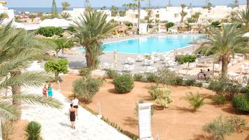 A resort with a swimming pool, palm trees, and lounge chairs.