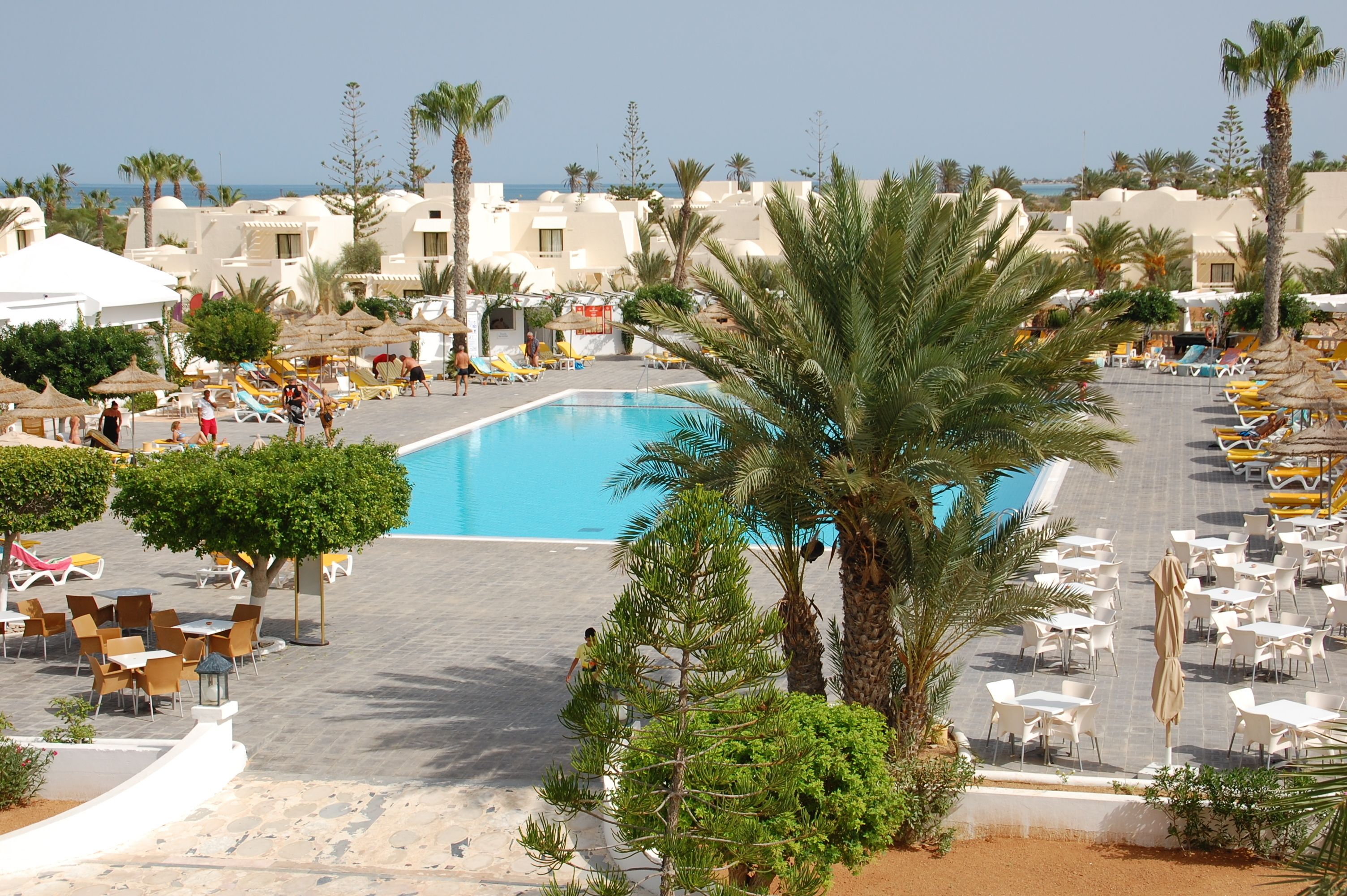 Un resort con piscina rodeada de palmeras y tumbonas.