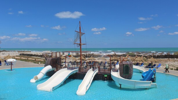 Une piscine dotée de plusieurs toboggans et de chaises longues.