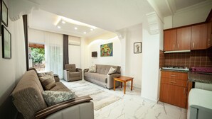 A modern living room with a sofa, a coffee table, and a dining area with wooden cabinets. - Zeybek 2 Pension & Apart (Kas)