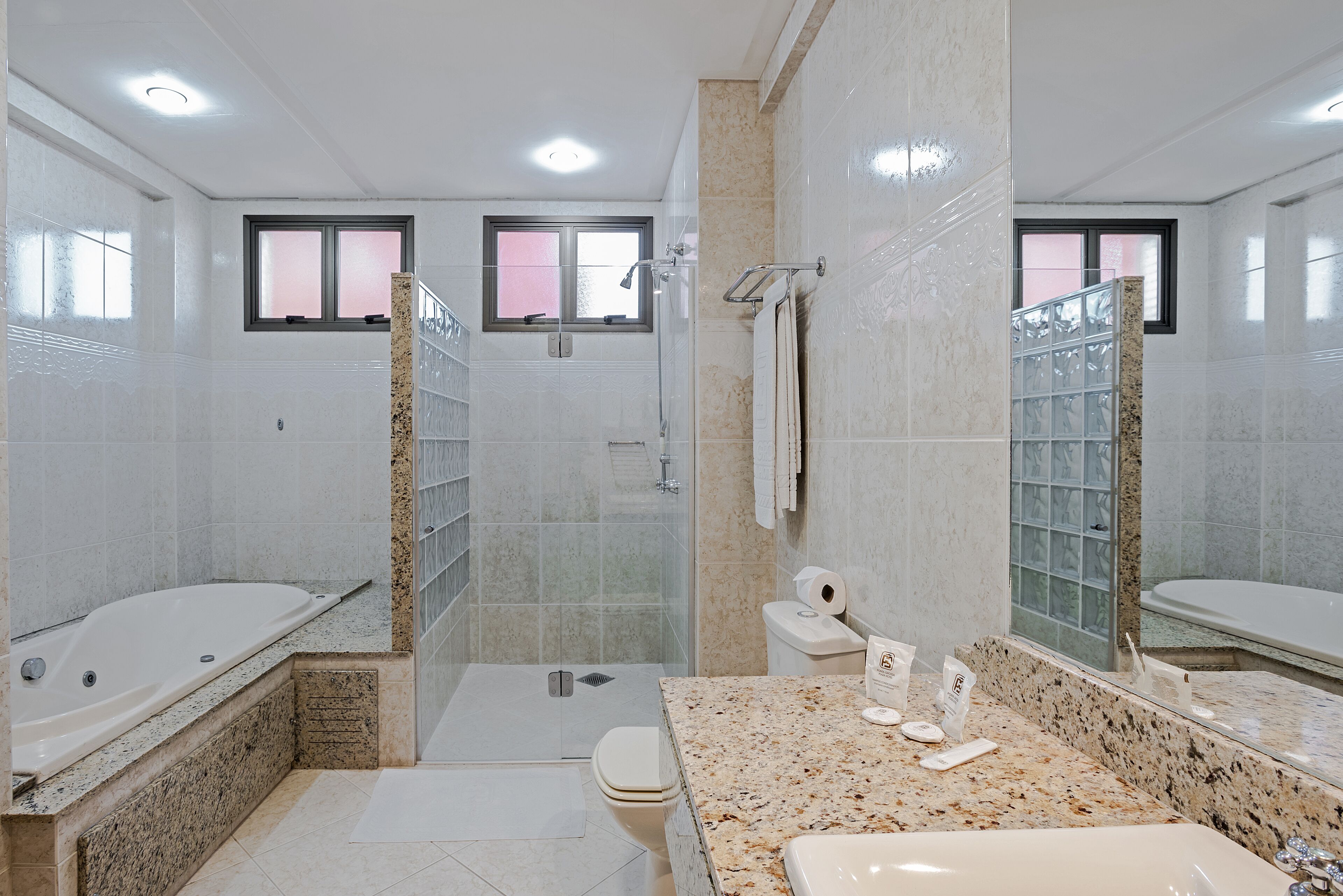 A modern bathroom with a bathtub, shower, toilet, and a vanity with a sink.