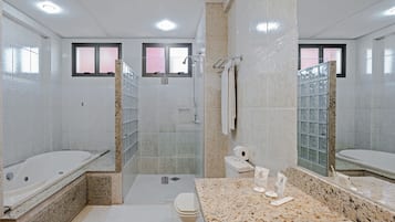 A modern bathroom with a bathtub, shower, toilet, and a vanity with a sink.