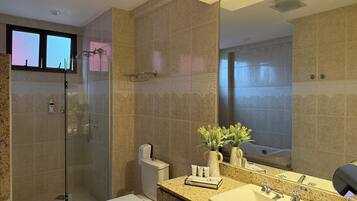 A modern bathroom with a glass shower enclosure, a toilet, a sink with a vanity, and a large mirror.