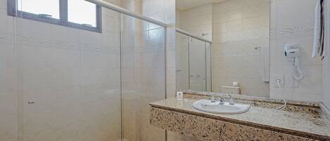 Un baño moderno con cabina de ducha de vidrio, encimera de granito y un espejo grande.