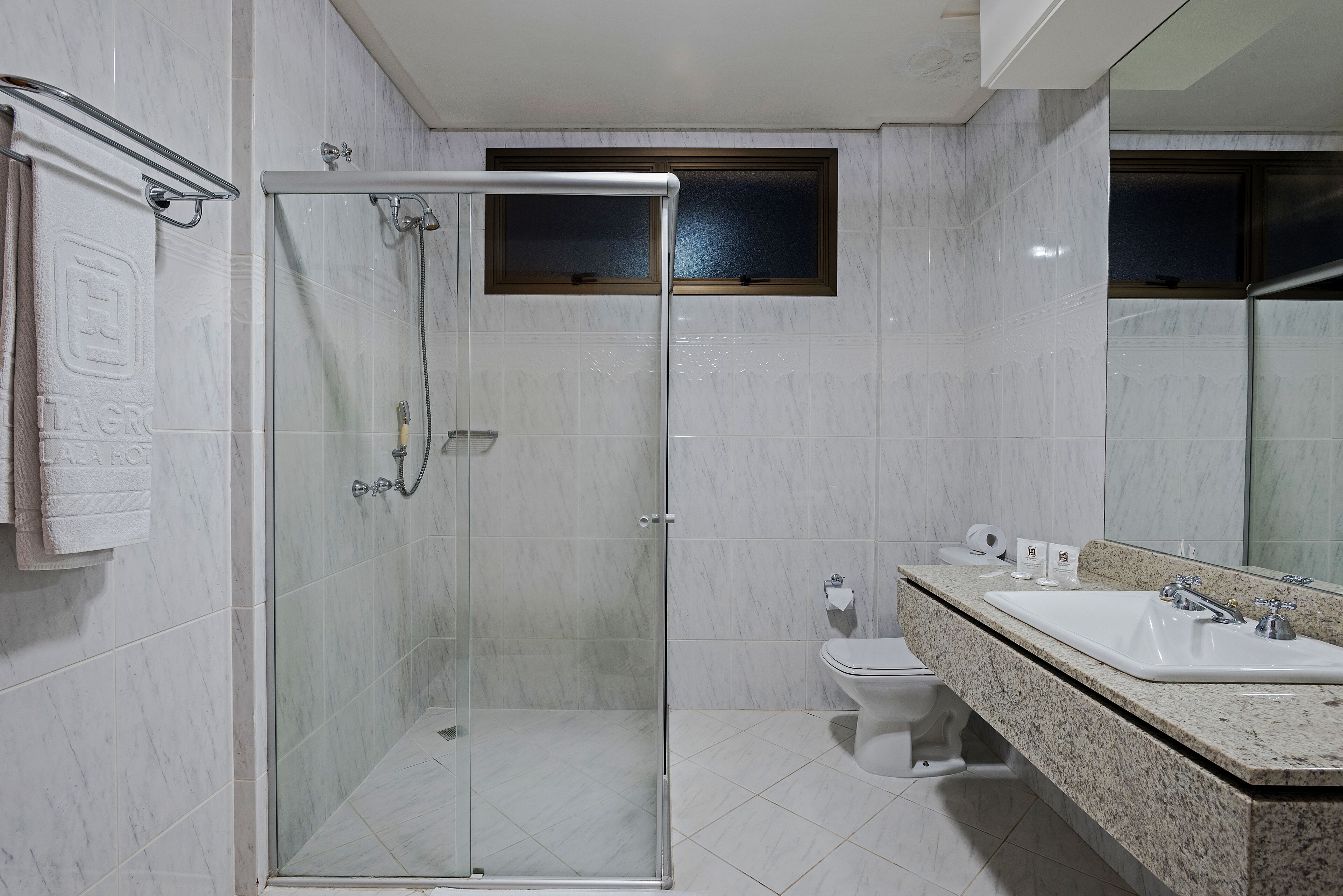 Un baño moderno con cabina de ducha de vidrio, inodoro y lavabo con encimera de granito.