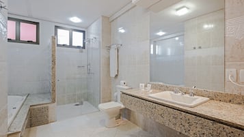 Uma casa de banho moderna com chuveiro, sanita e lavatório.