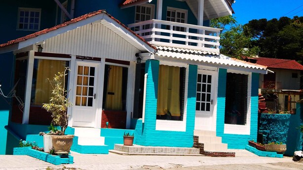 A two-story house with a balcony, a porch, and a small garden area with potted plants.